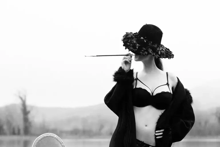 Modella in bianco e nero con cappello elegante e bocchino da sigaretta.