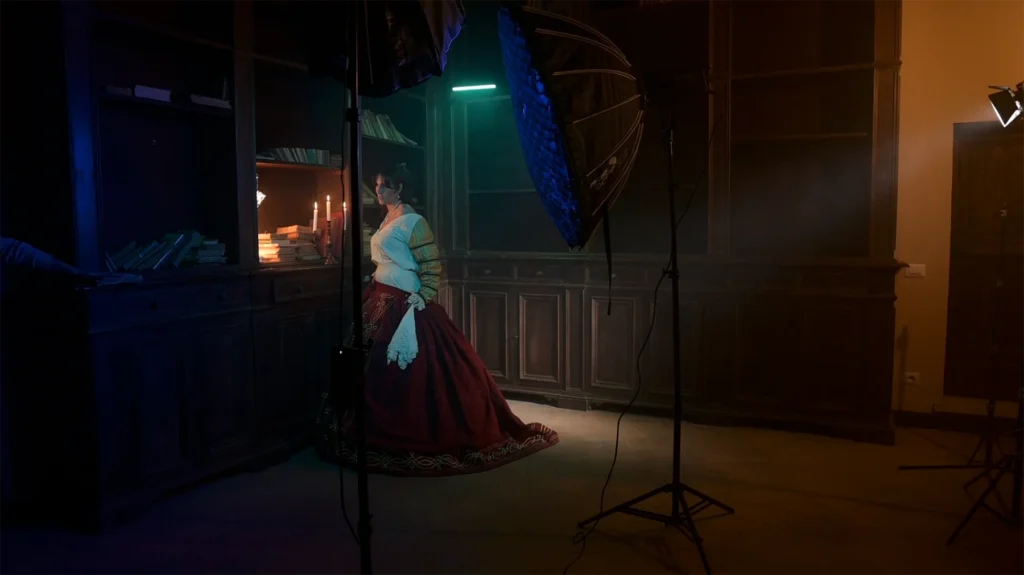 Backstage di un set fotografico cinema film con Luci cinematografiche per la fotografia di taglio cinematico con una dama del 1500 vicino alla luce di candela e luci artificiale con colori complementari in una biblioteca dell'antico palazzo Cesi . Direzione della fotografia di illuminotecnica fotografica con Francesco Francia fotografo di moda e direttore della fotografia DOP docente di fotografia